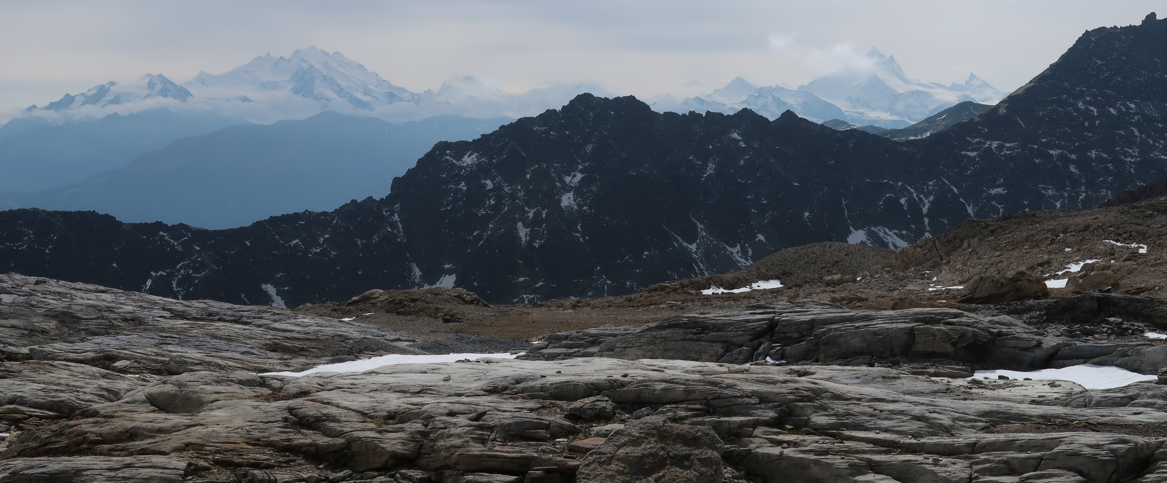 A flat area with smooth rock ground and snow mountains in the middle and far distance